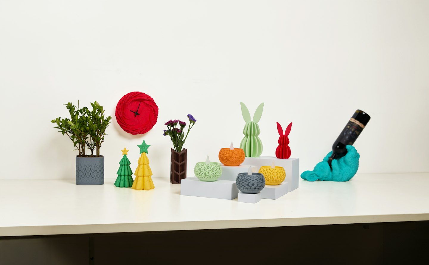 Colorful 3D printed objects and plants on a white table.