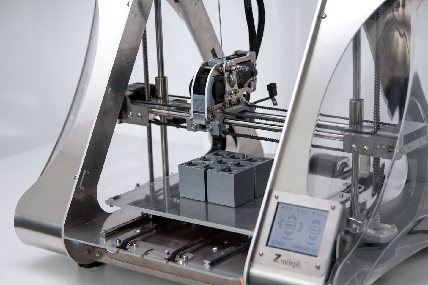 A 3D printer creating grey objects on its platform.