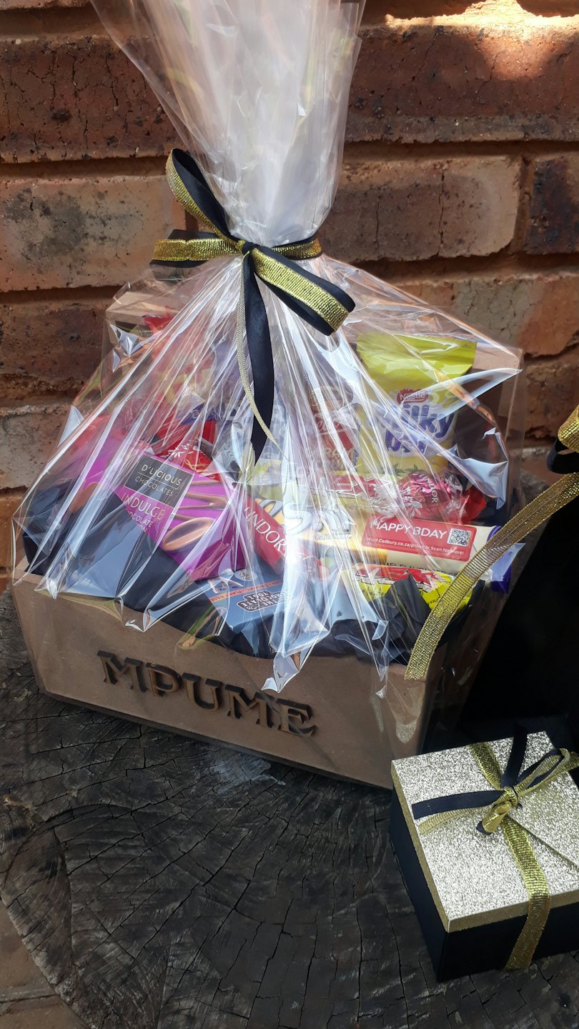 A gift basket of chocolates sits beside a small box.