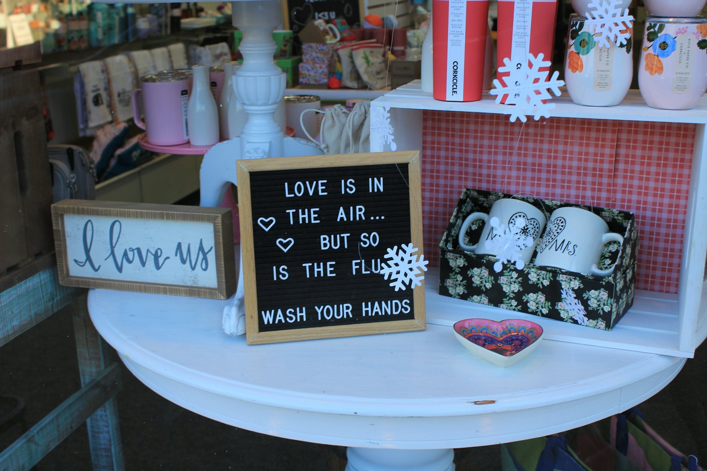 Gift mugs and signs arranged on a white round table.
